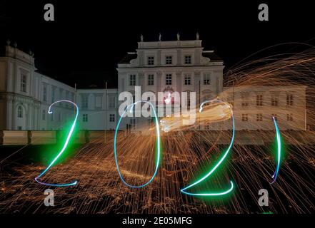 Oranienburg, Germania. 29 Dic 2020. Una donna ha disegnato l'anno 2021 con una torcia di fronte al Castello di Oranienburg (Brandeburgo). (Esposizione a lungo termine) credito: Paul Zinken/dpa/Alamy Live News Foto Stock