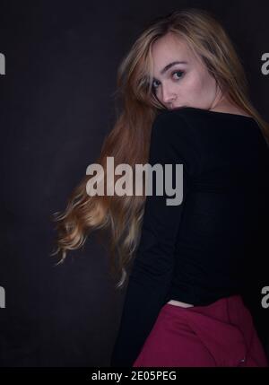 Immagine da studio di moda con un forte collegamento visivo che si affaccia sulla spalla con capelli lunghi che scorrono con una giovane donna naturalmente bella (20) Foto Stock