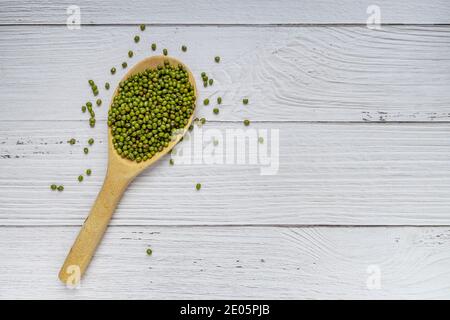 Fagioli verdi in cucchiaio di legno su fondo di legno bianco. Vista dall'alto. Concetto di cibo vegano Foto Stock