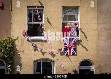 Persone che si appendono fuori da una finestra che sventola alle folle durante il matrimonio del Principe Harry e di Meghan Markle tenutosi il 19 maggio 2018 al Castello di Windsor, Regno Unito. Foto Stock