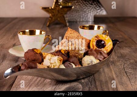 Silver Bowl pieno di biscotti natalizi e Golden Cups on Un tavolo di legno Foto Stock