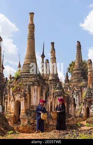 Giovani Pa o Signore che trasportano i cestini che camminano intorno Stupas al complesso di Pagoda di Shwe Indein, Stato di Shan, Lago di Inle, Myanmar (Birmania), Asia in febbraio Foto Stock