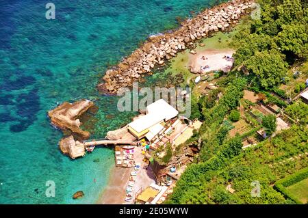 La riva dell'isola di Capri con un mare turchese trasparente, spiagge sabbiose e verde terra, vista dall'alto della costa, vista aerea Foto Stock