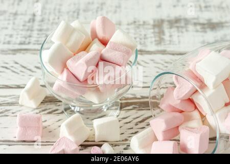 Marshmallow rosa e bianco assortiti in bicchieri su sfondo di legno. Marshmallow a forma di cuore per cioccolata calda o cacao. Foto Stock