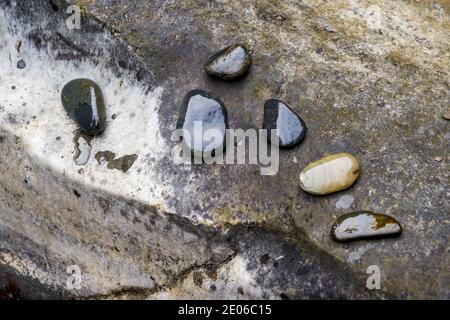 Primo piano di ciottoli sulla piana delle maree vicino al fiume Foto Stock