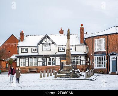 Le persone che camminano oltre le antiche croci di pietra sassone nel Piazza del mercato ricoperta di neve in inverno a Sandbach Cheshire Inghilterra Foto Stock