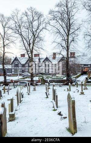 Il cimitero innevato e le lapidi nella parrocchia di Santa Maria chiesa Sandbach Cheshire Inghilterra in inverno guardando verso il Vecchio Sala pub e ristorante Foto Stock