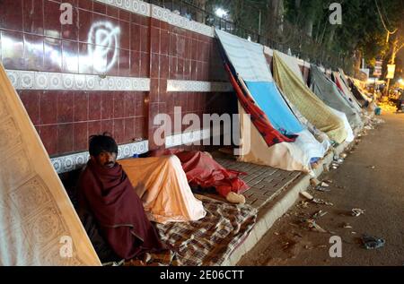 I pazienti e gli assistenti sono seduti in una tenda improvvisata per proteggersi dalle onde fredde della stagione invernale, fuori dall'ospedale Jinnah di Karachi mercoledì 30 dicembre 2020. Il Dipartimento Meteorologico del Pakistan ha detto che la metropoli ha assistito alla notte più fredda dell'anno e che le condizioni climatiche fredde e secche dovrebbero continuare nella città nelle prossime 24 ore. Foto Stock