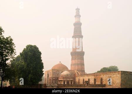 Il Qutb Minar, il minareto più alto del mondo, avvolto dalla nebbia mentre l'alba si rompe a Delhi, in India. Foto Stock