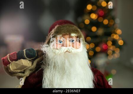 Babbo Natale porta una borsa grande piena di regali, a casa vicino a Natale Foto Stock