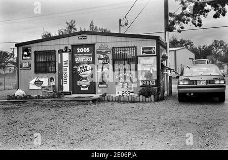 Drive Thru Drive nel fast food 1990s USA. Donna che si piega e serve un cliente nella sua auto. Sweetwater, Texas 1999 US. Il viaggio attraverso l'edificio del fast food coperto da cartelloni pubblicitari per la vendita di sigarette HOMER SYKES Foto Stock