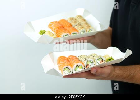 Concetto di consegna del sushi, l'uomo del corriere tiene i set di sushi in contenitori ecologici di carta Foto Stock