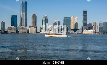 New York, Stati Uniti, dicembre 2020. Una barca turistica sul fiume Hudson con uno sfondo degli edifici Colgate Clock e Jersey City Highrise, durante il C. Foto Stock