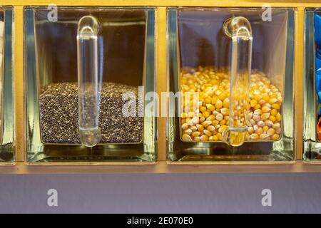 Due contenitori di cibo di vetro in una mensola di legno che mostra grano di mais giallo e una miscela di semi di quinoa bianchi e neri. Sfondo di cibo con spazio di copia Foto Stock