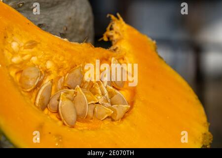 Molto vicino e messo a fuoco su un pezzo di zucca affettato con i semi. La polpa arancione del frutto è fresca e succosa. Sfondo di cibo con spazio di copia Foto Stock