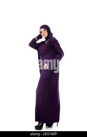 Viola. Bella donna araba in posa in elegante hijab su sfondo studio con copyspace per l'annuncio. Moda, bellezza, stile. Modello femminile con make up alla moda, manicure e accessori. Foto Stock