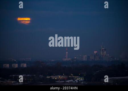 Birmingham, Regno Unito. 30 dicembre 2020. La luna piena di prima sera si infrangono tra le nuvole mentre inizia la sua apparizione che si erge su un centro della città di Birmingham coperto di neve destinato domani alla sua nuova restrizione Tier 4. Credit: Lee Hudson/Alamy Live News Foto Stock