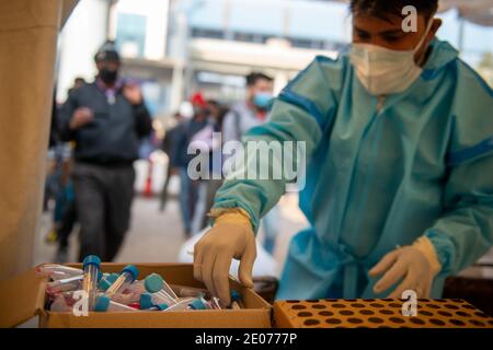 Un operatore sanitario in kit PPE che raccoglie campioni presso un campo di test gratuito Covid-19 presso il terminal degli autobus Anand vihar.Delhi conduce test casuali di coronavirus a terminal degli autobus, stazioni ferroviarie, fuori stazioni della metropolitana, ecc. Foto Stock