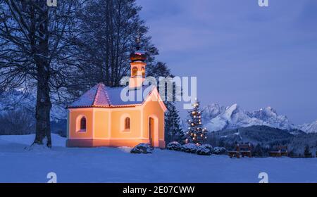 Albero di Natale vicino alla bella chiesa in montagna - notte illuminata dal luna Foto Stock