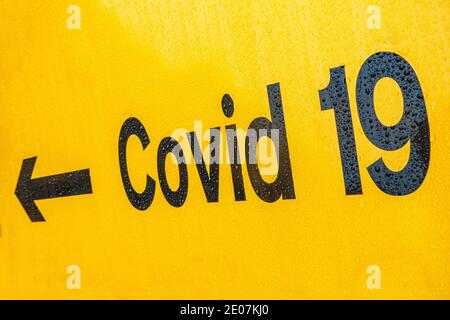 Segui le indicazioni per Covid 19 con la freccia sul cartello giallo In Inghilterra Foto Stock