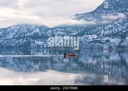 Penticton, British Columbia/Canada - 28 dicembre 2020: Una persona pagaia un kayak attraverso il lago Skaha durante la calma dopo una tempesta invernale. Il lago è o Foto Stock