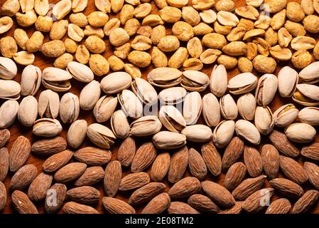 Orizzontale di arachidi arrostite, mandorle, pistacchi su tavola di legno Foto Stock