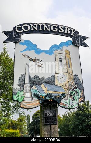Segno del villaggio di Coningsby, associato con RAF Coningsby e raffigurante aerei della Royal Air Force Battle of Britain Memorial Flight, chiesa Foto Stock