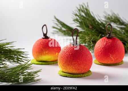 Tre dolci mousse sotto forma di palle di Natale su sfondo bianco. Festa di Capodanno. Formato orizzontale Foto Stock