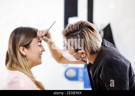 Cosmetologa latina che si prepara alla donna messicana per la procedura di trucco permanente sopracciglia in Messico, closeup Microblading Foto Stock