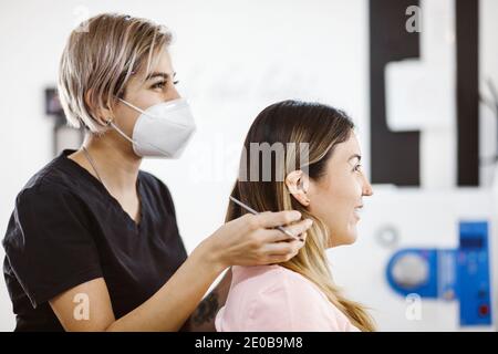 Cosmetologa latina che si prepara alla donna messicana per la procedura di trucco permanente sopracciglia in Messico, closeup Microblading Foto Stock