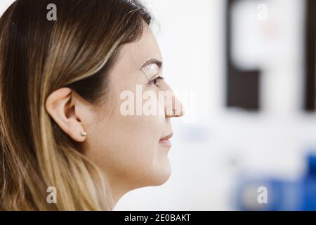 Cosmetologa latina che si prepara alla donna messicana per la procedura di trucco permanente sopracciglia in Messico, closeup Microblading Foto Stock