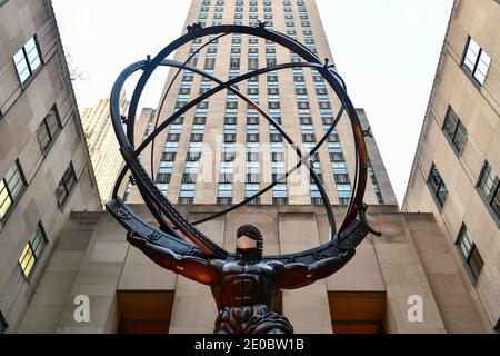 New York, NY - Nov 14, 2020: La ditta di bene immobile Tishman Speyer ha montato le maschere sull'atlante ed altre statue classiche nel centro del Rockefeller per incoraggiare New Yo Foto Stock