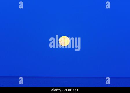 La luna piena di fragole sorge sull'Oceano Atlantico Foto Stock