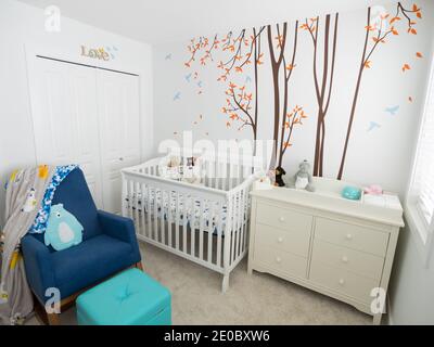 Una moderna camera da letto per bambini decorata con una culla, un comò, un pannolino cambio tavolo, sedia dondolo, e nessuna gente. Foto Stock