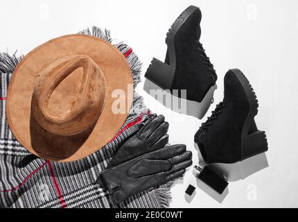 guardaroba autunnale. Articoli da donna, scarpe e accessori su sfondo bianco. Cappello in feltro, stivali in pelle scamosciata, guanti in pelle, una bottiglia di profumo, sciarpa. Piatto Foto Stock