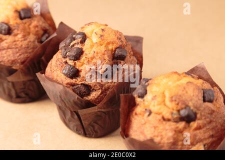 Tre muffin al cioccolato su sfondo marrone. Foto Stock