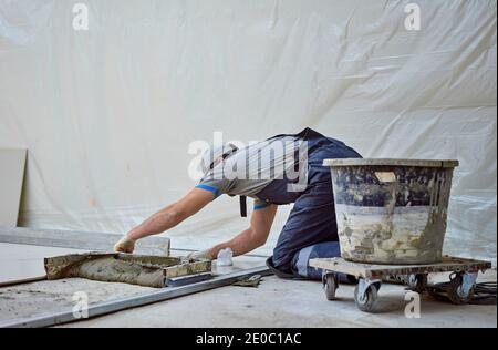 l'uomo pone il gres su un luogo di costruzione Foto Stock