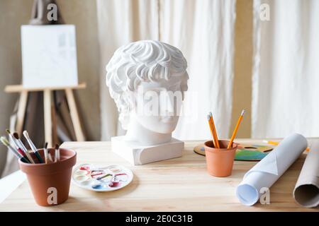 Interier per studio d'arte con testa in gesso, pennelli e carta whatman sul tavolo. Foto Stock
