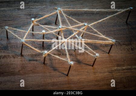 un'immagine simbolo per il lavoro di gruppo e di rete. i chiodi sono collegati da spago di iuta. tenere insieme. Foto Stock