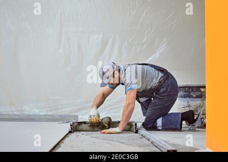 l'uomo pone il gres su un luogo di costruzione Foto Stock