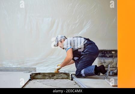 l'uomo pone il gres su un luogo di costruzione Foto Stock