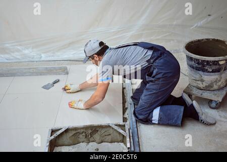 l'uomo pone il gres su un luogo di costruzione Foto Stock