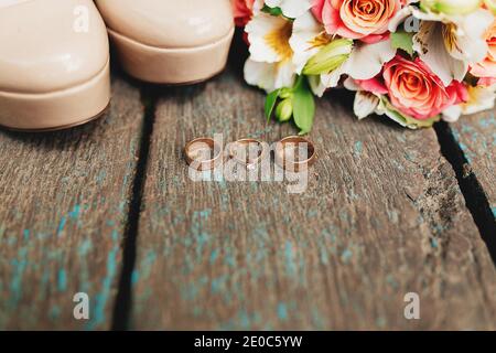 Anelli di nozze, scarpe e bouquet su sfondo di legno Foto Stock