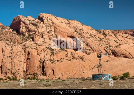 Il mulino a vento e acqua del serbatoio, lo scheletro Mesa dietro, Navajo Indian Reservation, vicino a Kayenta, Arizona, Stati Uniti d'America Foto Stock