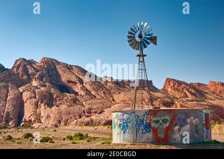 Il mulino a vento e acqua del serbatoio, lo scheletro Mesa dietro, Navajo Indian Reservation, vicino a Kayenta, Arizona, Stati Uniti d'America Foto Stock