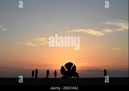 La gente guarda l'alba accanto allo Scallop, scultura di Maggi Hambling 2003, che commemora Benjamin Britten, Aldeburgh, Suffolk, Inghilterra Foto Stock