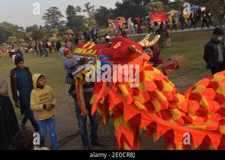 Lahore, Pakistan. 30 dicembre 2020. Pakistani un gran numero di famiglie siedono a terra partecipa al "Festival degli inverni di famiglia" al circuito automobilistico Jilani Park nella capitale provinciale Lahore. Le famiglie si divertono con il modello Dinosaur e lo spettacolo Breathing Fire from Mouth durante il "Family Winters Festival" all'ippodromo Jilani Park. (Foto di Rana Sajid Hussain/Pacific Press) Credit: Pacific Press Media Production Corp./Alamy Live News Foto Stock