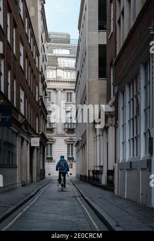 Londra, UK - Dicembre 2020 : l'uomo scende in bicicletta lungo una corsia nella City di Londra durante il blocco Tier 4 Foto Stock