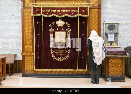 Un uomo ebreo non identificato in uno scialle di preghiera prega di fronte all'Arca Santa ornata presso la sinagoga principale di Lubavitch a Crown Heights, Brooklyn, New York. Foto Stock