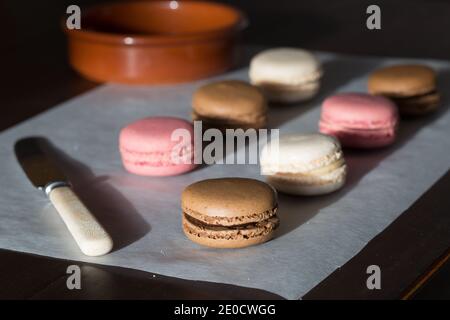 Un primo piano di cibo di macaron fatti in casa appena sfornati o Macaron in cioccolato, vaniglia e rosa Foto Stock